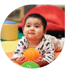 Smiling infant holding a ball