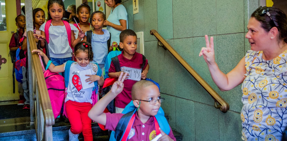 A teacher counts off her students as they file out of a building