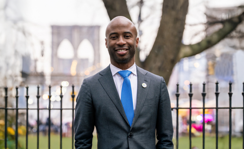 Chancellor Samuels in a suite with blue tie garden and brooklyn bride in background