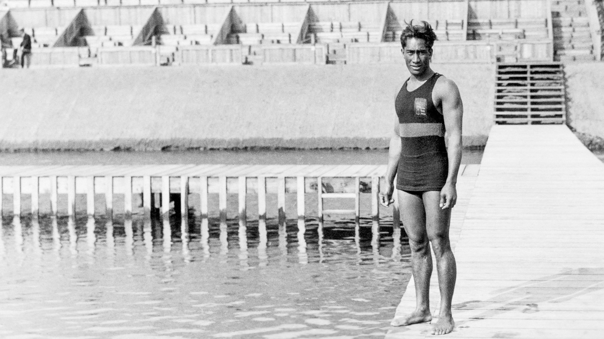 Duke Kahanamoku standing poolside at the Olympics.