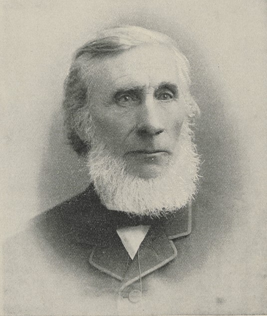 Black and white photograph of John Tyndall, a man with a large white beard wearing a dark suit with a serious expression.