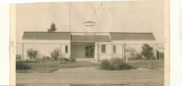 Black and White Photograph of the Hoover School in Orange County, California in 1944. It is a plain white school building behind a fence.
