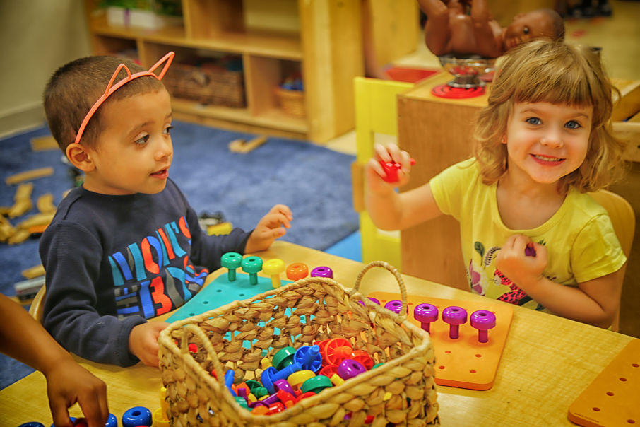 Young children playing with pegs and board