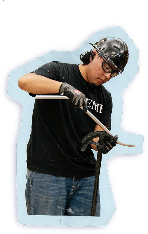 A student wearing safety equipment works carefully with tools