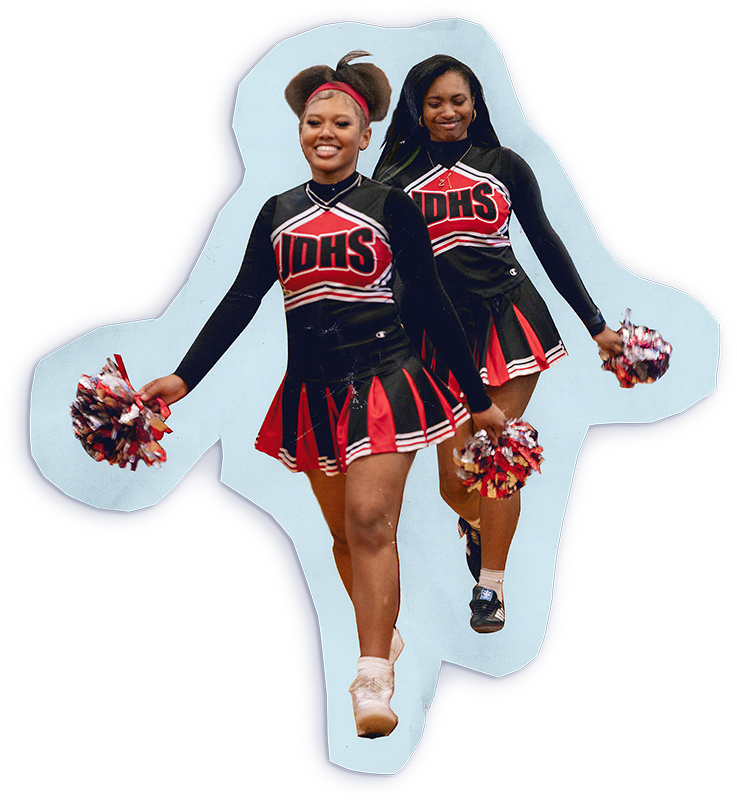 Two cheerleaders holding pom poms in each hand walking proudly
