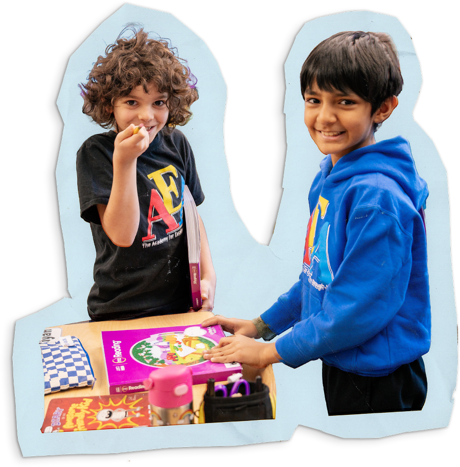 Two children holding reading workbooks smiling