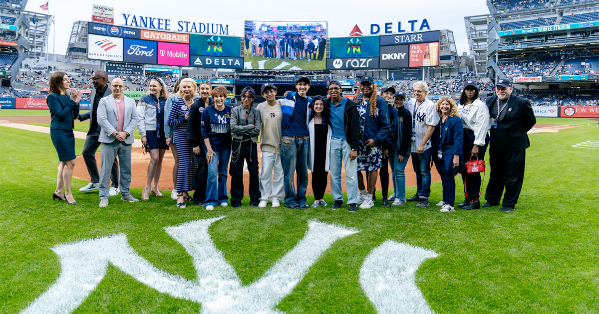 Large gathering of people near home plate at Yankee Stadium featuring the five winners of the 2025 Yankees Stonewall Scholarship initiative.