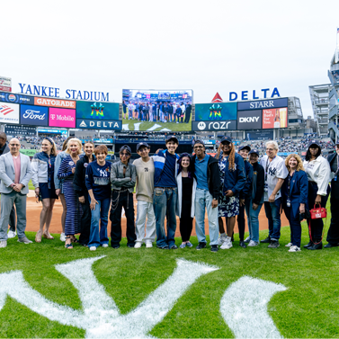 Large gathering of people near home plate at Yankee Stadium featuring the five winners of the 2025 Yankees Stonewall Scholarship initiative