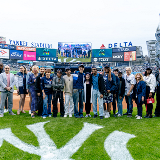 Large gathering of people near home plate at Yankee Stadium featuring the five winners of the 2025 Yankees Stonewall Scholarship initiative
