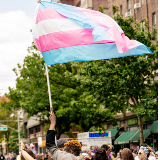 A person waving a transgender flag at a Pride parade