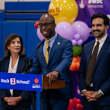 Photo featuring Governor Kathy Hochul (left), Chancellor Kamar Samuels (center), and Mayor Zohran Mamdani (right) standing at a podium and smiling.