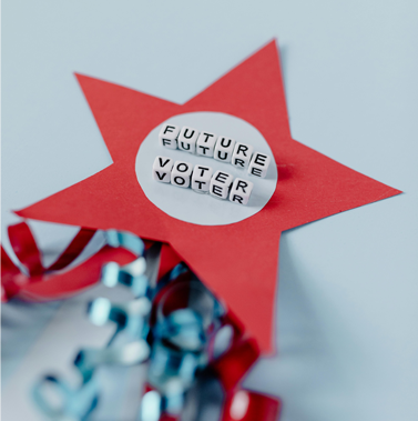 Close-up of a crafted red star featuring glued-on block letters that spell out "Future Voter."