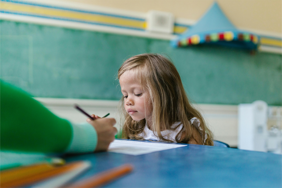 A young child learns from their teacher in their classroom