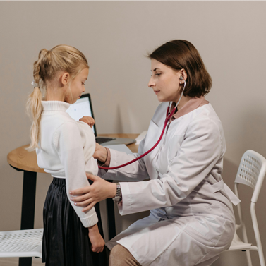 A medical professional (right) using a stethoscope to check a child (left).