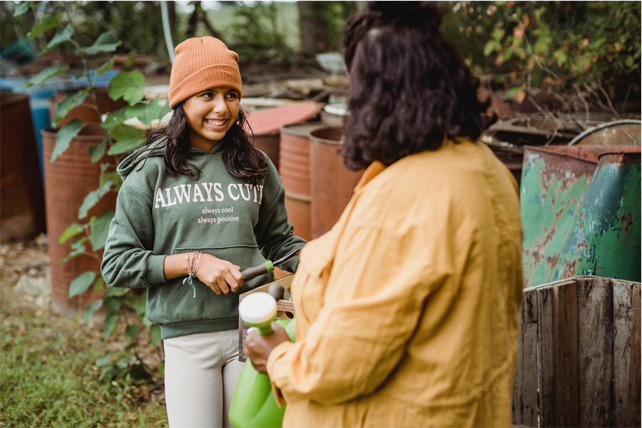 Young teenage girl (left) smiling as an older woman (right) talks to her about farming and planting.