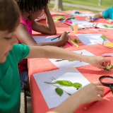 Students do artwork outside on a picnic table