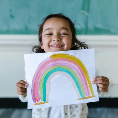 Young girl holding up a watercolor painting of a rainbow.