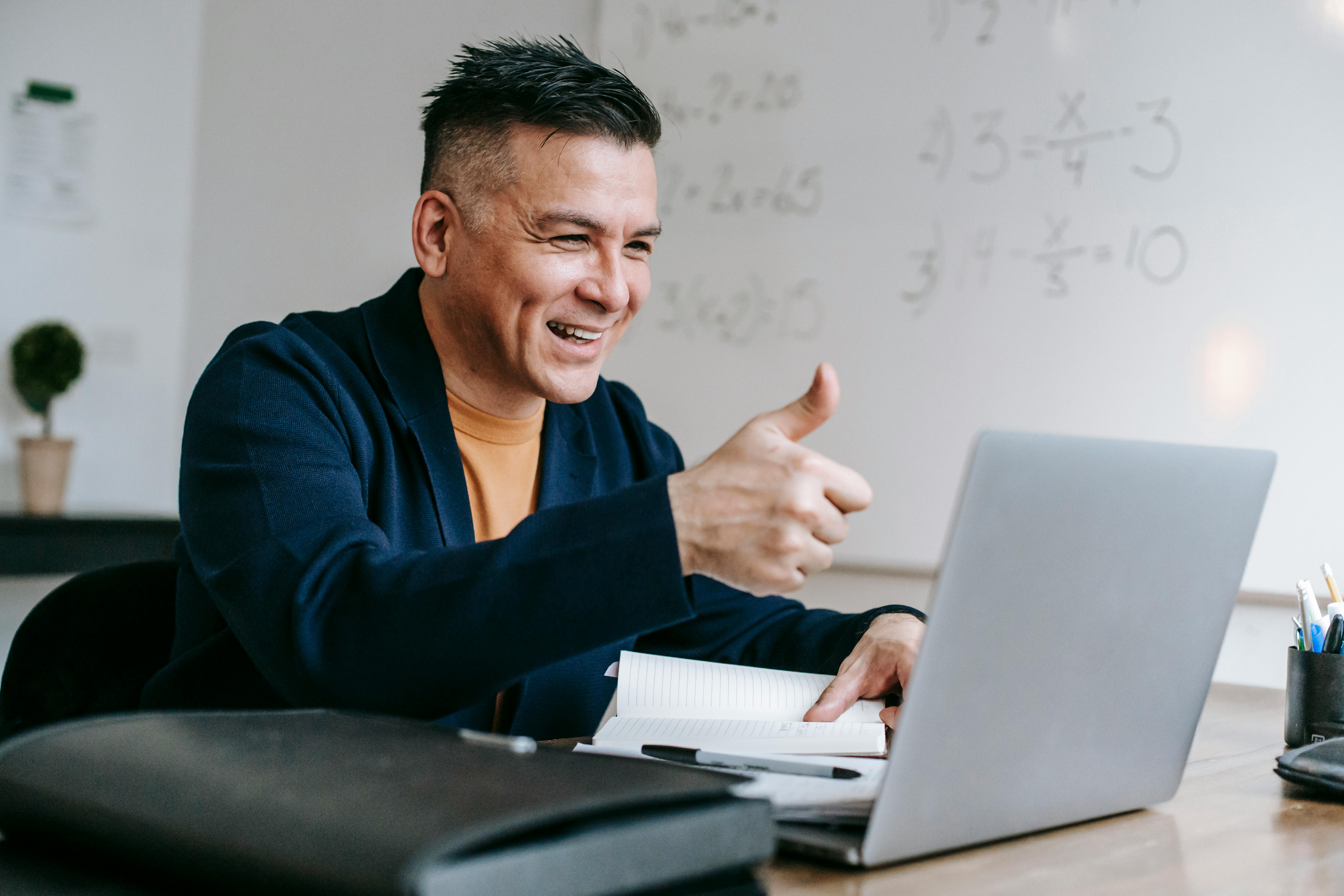 Man giving a thumbs up in a video conference on a laptop