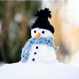 Close-up of a small snowman featuring a tiny felt hat and scarf, along with a mini carrot for a nose, and tiny black dots for eyes and coat buttons.