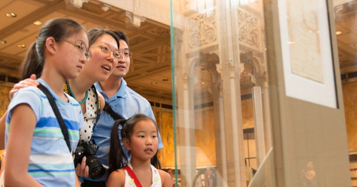 A family of four looking at an exhibition in a library to celebrate USA250.