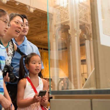 A family of four looking at an exhibition in a library to celebrate USA250.
