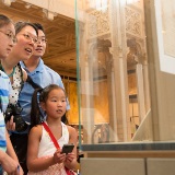 A family of four looking at an exhibition in a library to celebrate USA250.