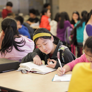 Female student reading a book at lunch.