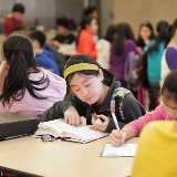 Female student reading a book at lunch.