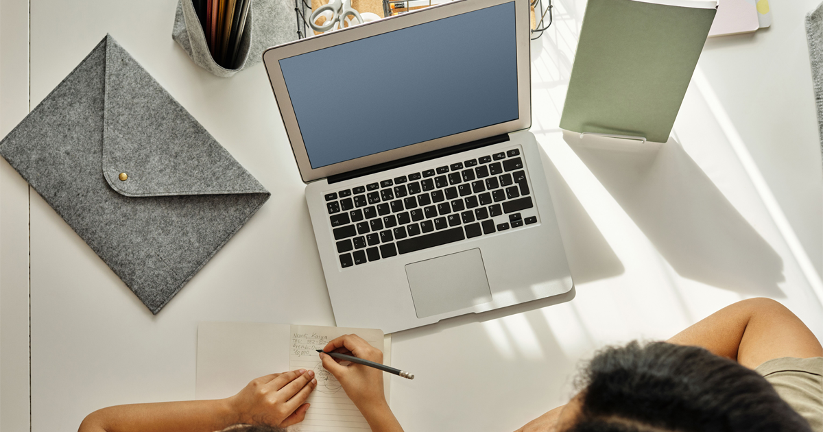 Overhead shot of an adult sitting with a child at a desk with a laptop on it.