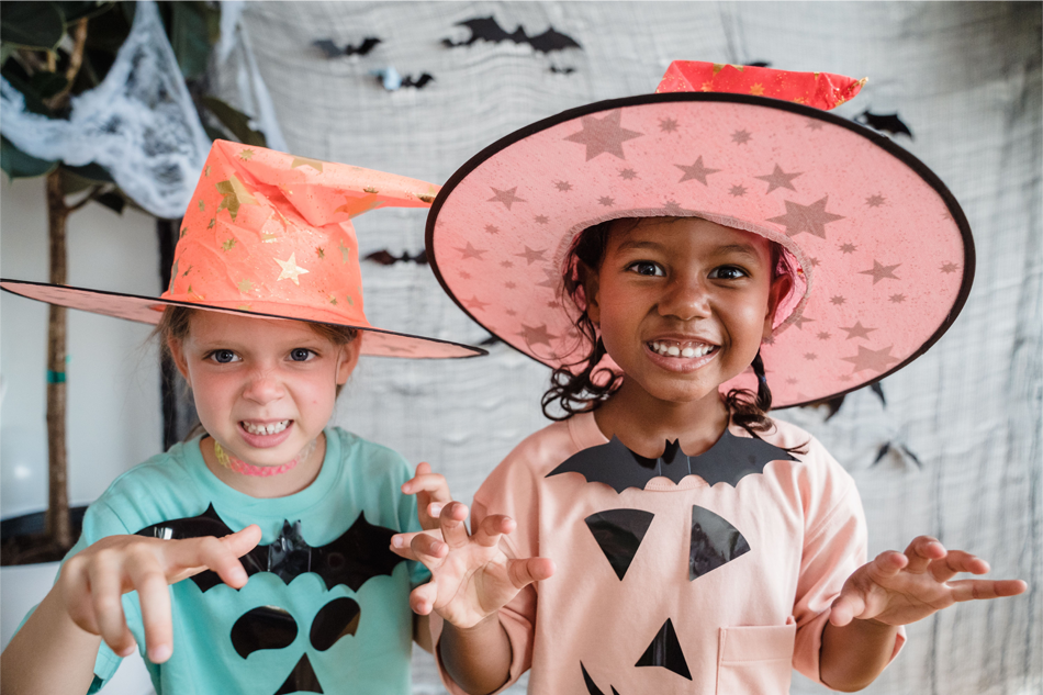 Two young girls wearing Halloween-inspired outfits while making 'spooky' faces.
