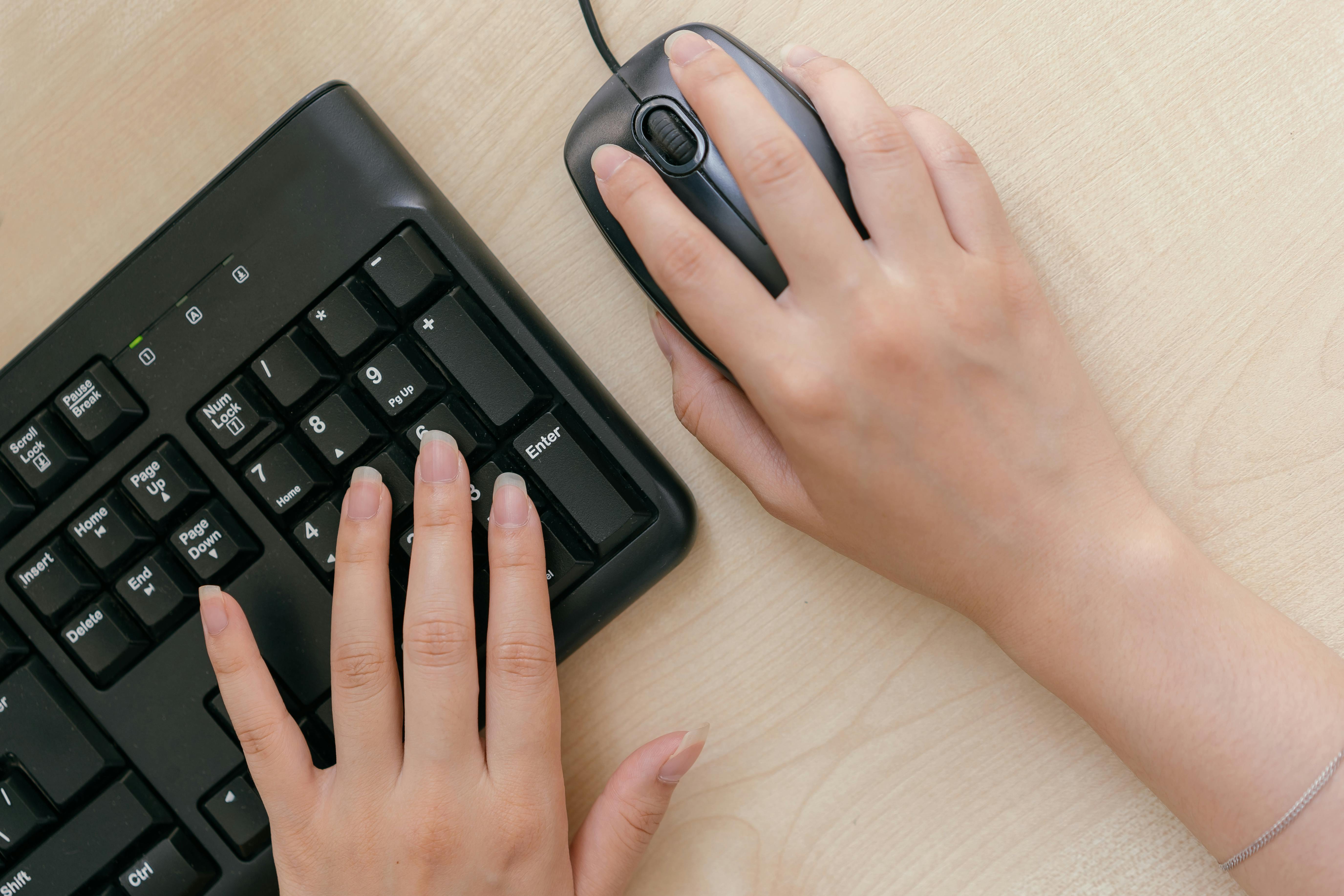 A person uses a computer keyboard and mouse