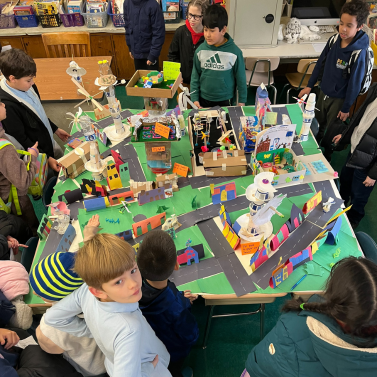 Students gathered around a table playing a hand-made boardgame themed around energy conservation.