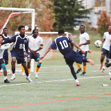 Group of boys playing soccer. The boy at the center wearing jersey number 10 is about to kick the ball, which is midair.