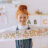 Young student holding up number cards with illustrations