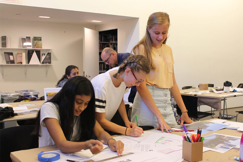 Three high school-aged girls working together at a large drafting table