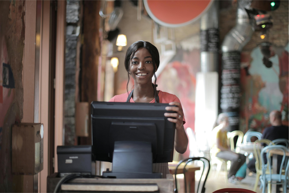 Teenaged Waitress Standing by a Point of Sale Spot in a Restaurant