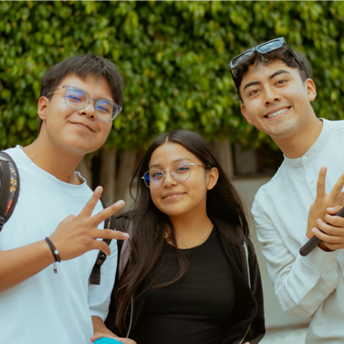 Three young people looking at viewer and smiling; one on right is holding a microphone.