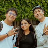 Three young people looking at viewer and smiling; one on right is holding a microphone.