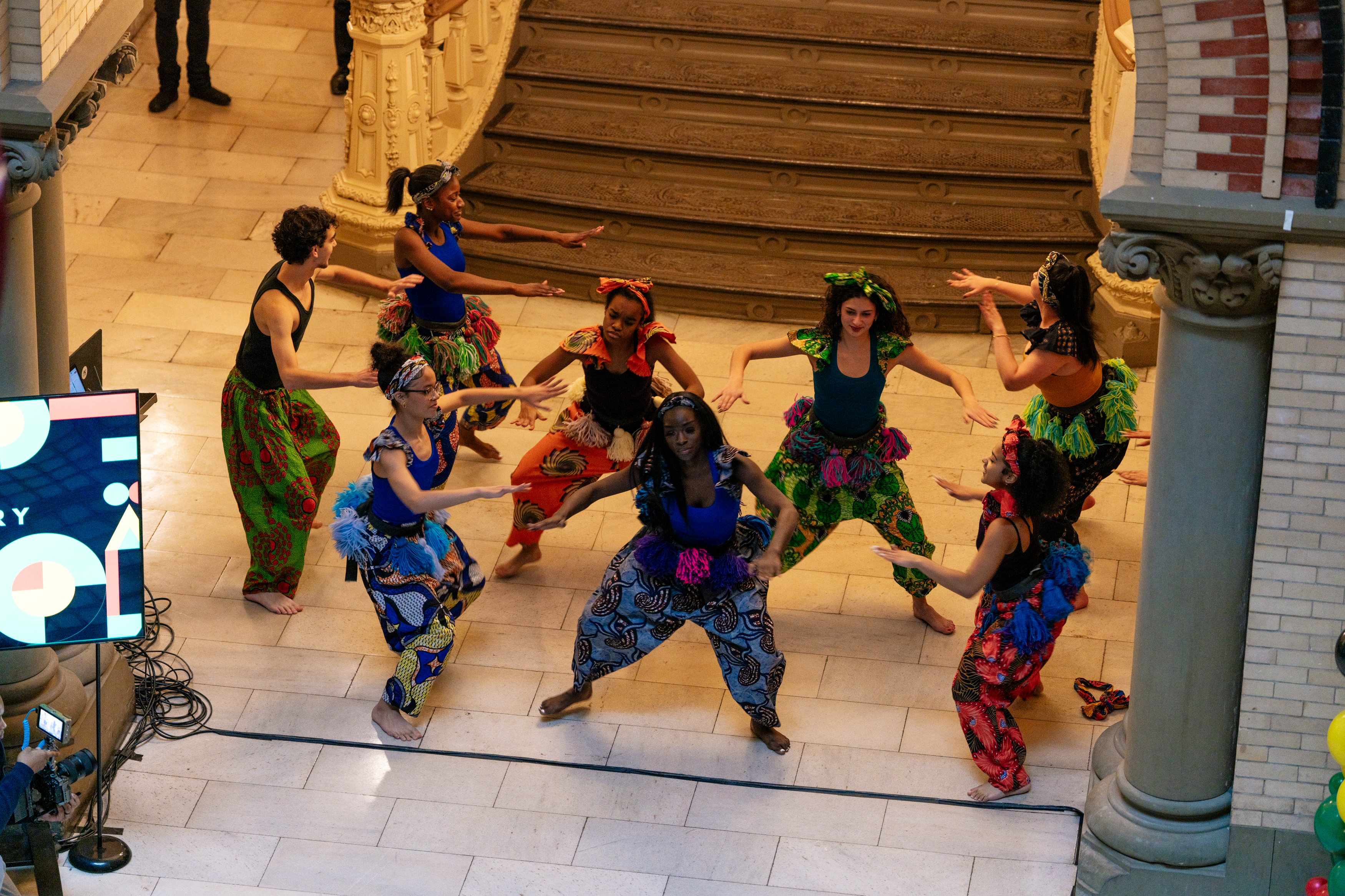 A group of student dancers dressed in colorful dance outfits performing.