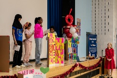 A group of students standing on a stage with anti-bullying signs and posters surrounding them.