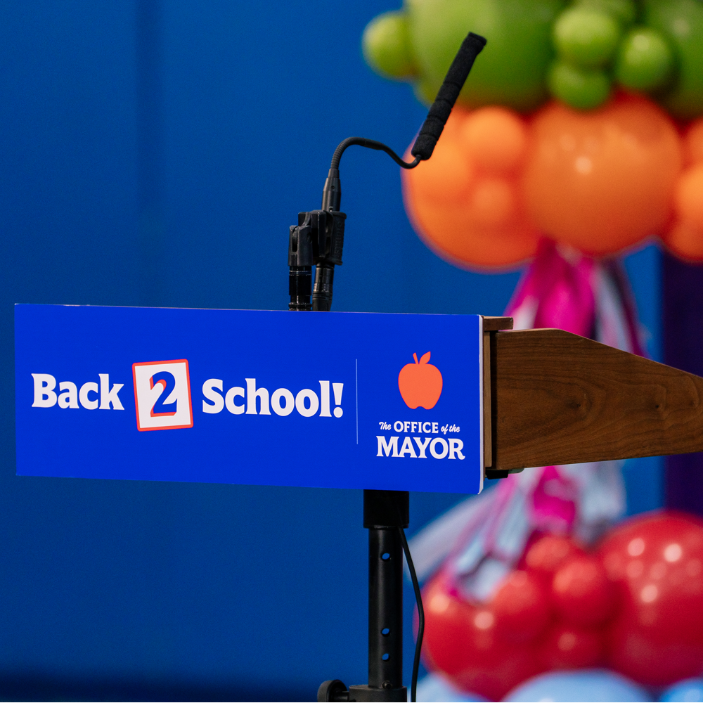 Close-up of a microphone podium featuring a lecturn sign that reads, 'Back 2 School!'
