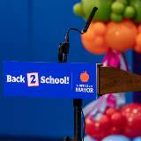 Close-up of a microphone podium featuring a lecturn sign that reads, 'Back 2 School!'