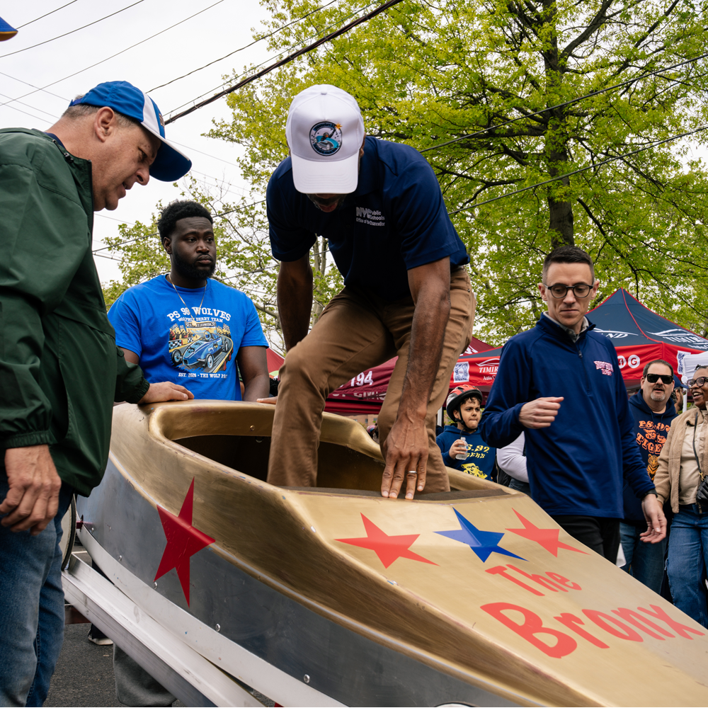 Chancellor Samuels climbing into a gold soap box car