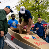 Chancellor Samuels climbing into a gold soap box car