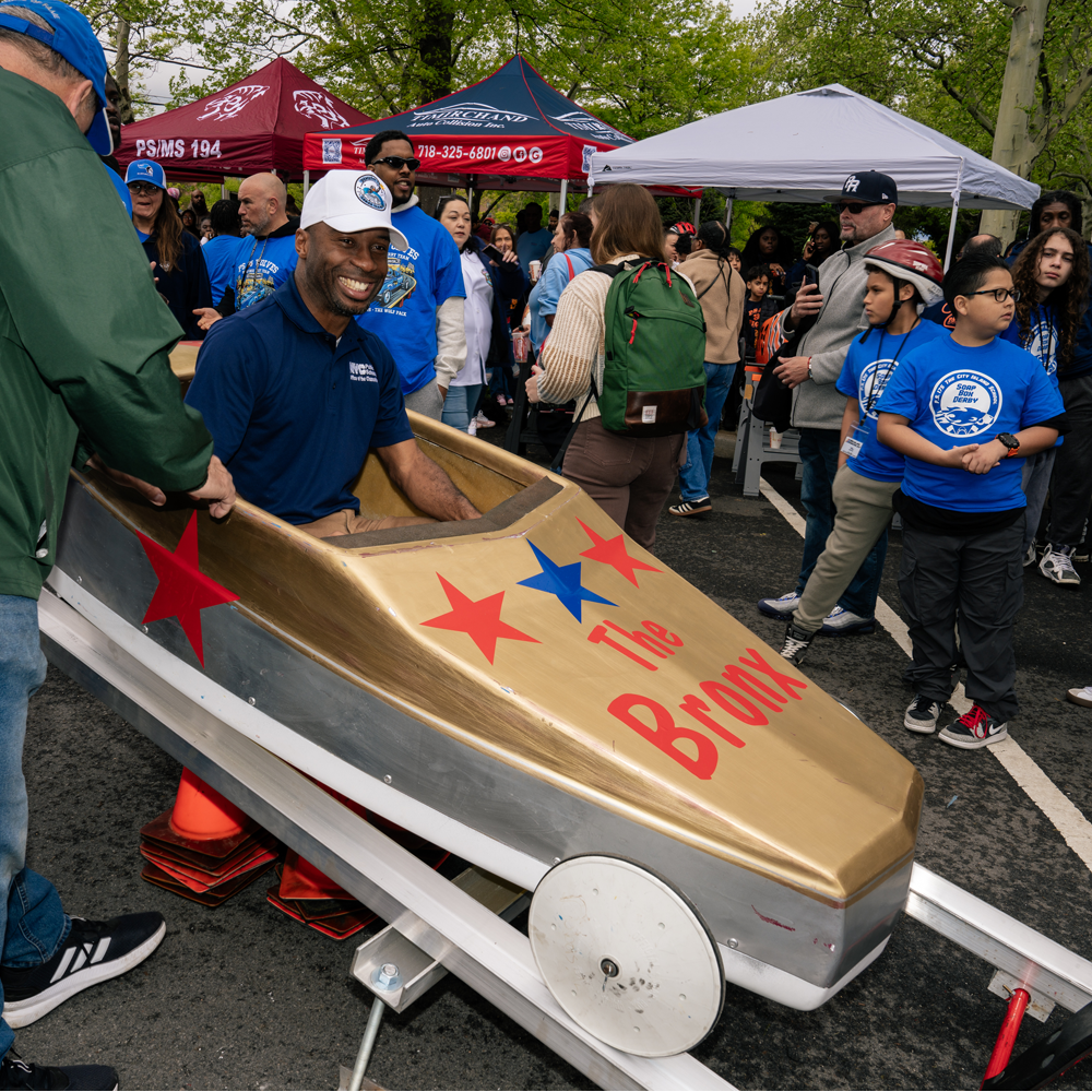 Chancellor Samuels smiling after settling into a gold soap box car