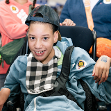 Closeup of a young elementary school-aged student sitting in a wheelchair and smiling