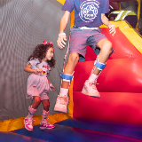 Two young students with leg braces jumping in a Bounce n Play during a Javits Center event for District 75 students and families