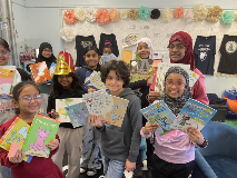 Group of 10 students holding up copies of their favorite books to read aloud