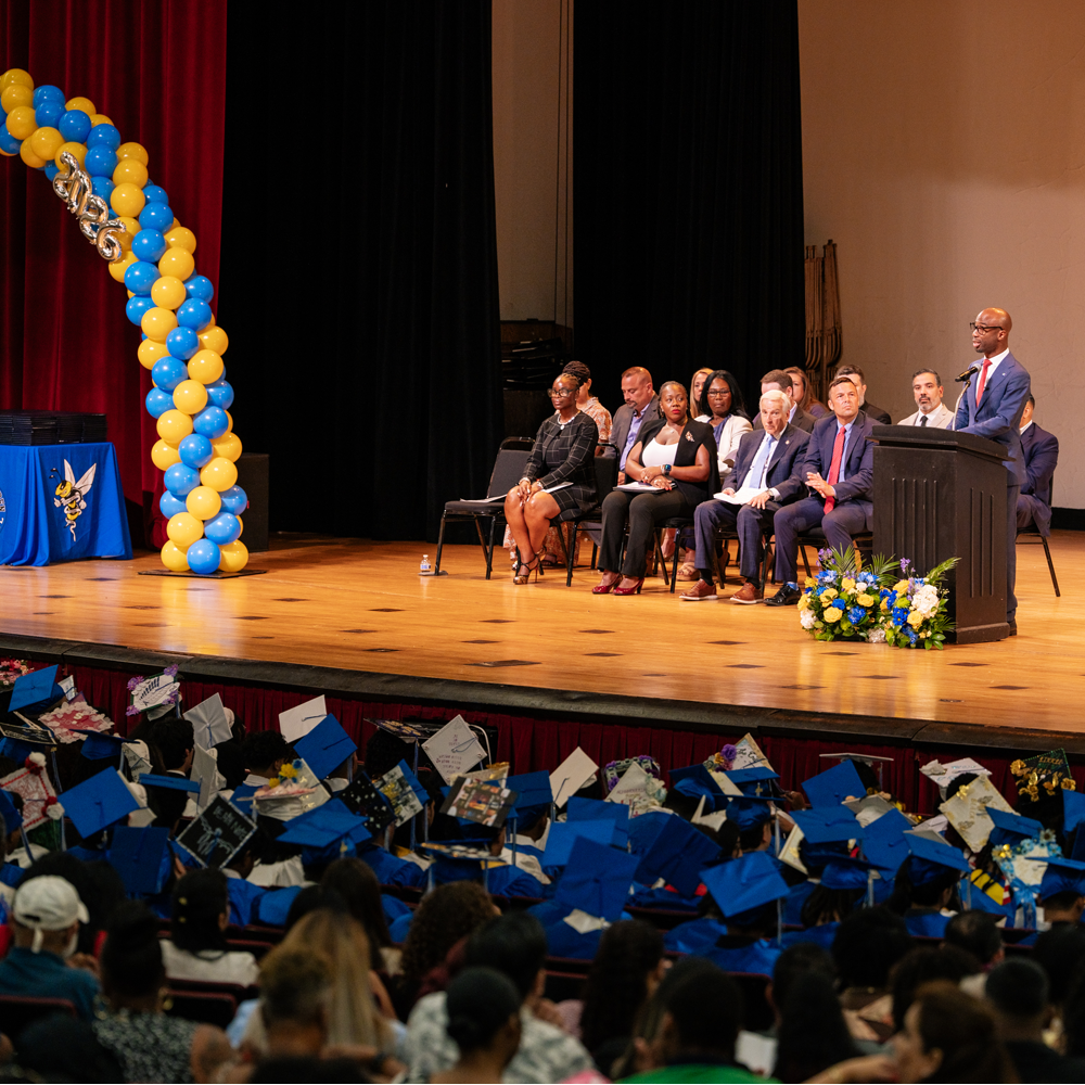 Chancellor Kamar Samuels delivering a speech at a podium during Martin Van Buren High School's 2026 graduation.