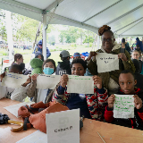 Five people holding up handwritten signs that show their climate action plans.